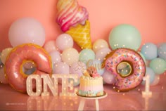 a birthday cake with frosting and sprinkles sits in front of balloons