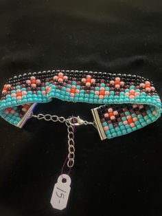 a blue and orange beaded bracelet with a tag on the clasp that is attached to it