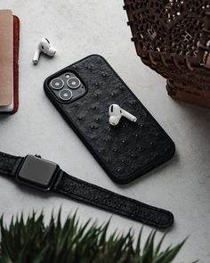 an iphone case with keys and earbuds on it next to a book, plant and headphones