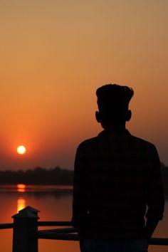 the man is looking out over the water at sunset