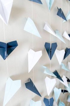 blue and white origami birds hanging from strings on the wall with paper streamers