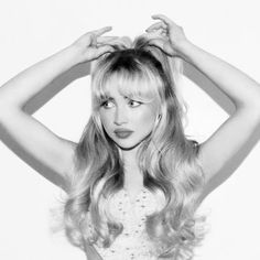 a black and white photo of a woman holding her hair in front of her head