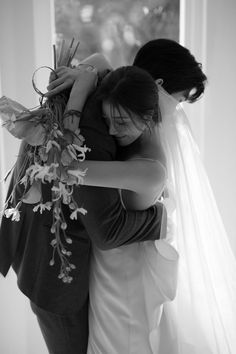 two women hugging each other in front of a window