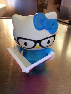 a hello kitty figurine holding a toothbrush on top of a wooden table