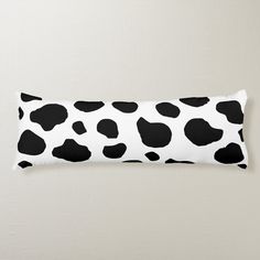 a black and white cow print pillow on a wall