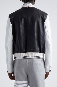 Thom Browne's signature varsity stripes create understated pops of color at the lining of this varsity-inspired bomber jacket boasting a rich lambskin body with soft wool sleeves. Front snap closure Blade collar Front welt pockets Ribbed cuffs and hem Cupro lining Leather with 100% wool contrast Dry clean Made in Italy Designer Clothing Luxury Varsity Jacket With Ribbed Cuffs For College, Designer Varsity Jacket With Ribbed Cuffs And Baseball Collar, Designer Varsity Jacket With Baseball Collar And Ribbed Cuffs, Luxury Varsity Jacket With Baseball Collar For Winter, Luxury Varsity Jacket With Baseball Collar, Luxury Streetwear Varsity Jacket With Padded Collar, Luxury Varsity Jacket With Padded Collar For Streetwear, Luxury Black Varsity Jacket With Padded Collar, Luxury Winter Varsity Jacket With Padded Collar