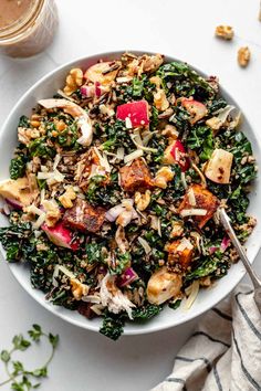 a white bowl filled with kale salad and nuts