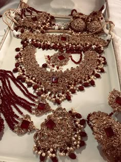 an assortment of red and gold jewelry on display in a white box at a jewelery shop