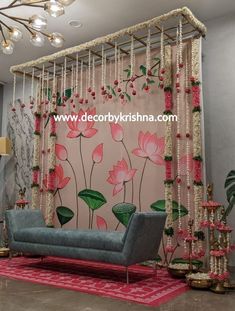 a living room decorated with pink flowers and pearls hanging from the ceiling, along with a blue couch