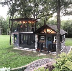 a small cabin in the middle of a field with trees and lights hanging from it's roof