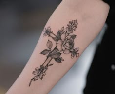 a black and white photo of a flower tattoo on the right arm, with flowers around it