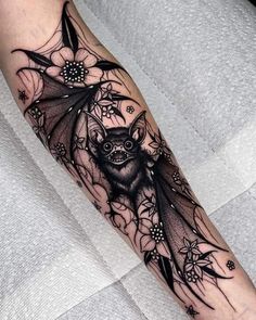 a bat tattoo on the arm with flowers