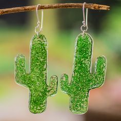 a pair of green cactus earrings hanging from a tree branch