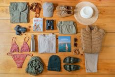 the contents of a woman's travel bag laid out on a wooden floor, including clothing and accessories