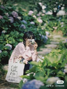 a woman taking a photo with her cell phone in a field full of purple flowers