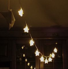 a string of stars is hanging from the ceiling in front of a window at night