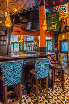 the interior of a bar with blue and yellow stools, black and white checkered floor