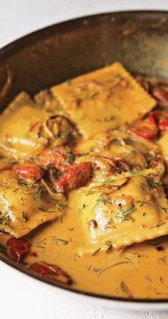 a pan filled with ravioli and vegetables on top of a stove