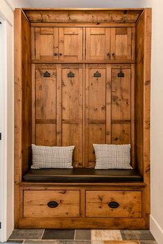 a wooden bench with two pillows on it in front of a large wood cabinet and door