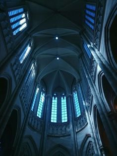 the interior of a cathedral with multiple windows and arches on each side, all lit up by blue lights