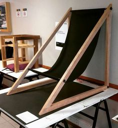 a black chair sitting on top of a table next to a wooden frame and plywood