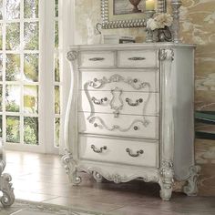 a white dresser sitting in front of a window next to a painting on the wall