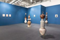 there are many vases on display in the room with blue walls and grey carpet