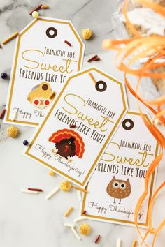 three tags with thanksgiving sayings on them sitting next to candy and sprinkles