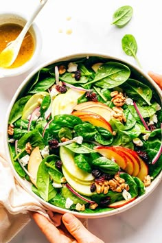 a bowl filled with spinach, apples and walnuts