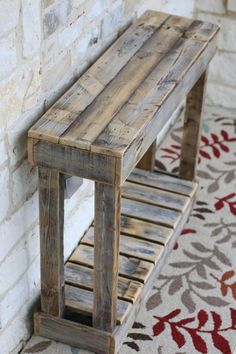 a wooden bench sitting in front of a brick wall next to a red and white rug