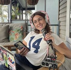 a woman with headphones on sitting in front of a laptop and holding a microphone