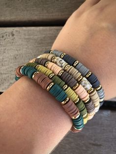 a woman's arm with several different colored bracelets on top of each other