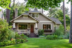 a small house in the middle of a lush green yard with trees and flowers around it