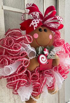 a brown teddy bear wearing a red and white tutu with a pink bow on it's head