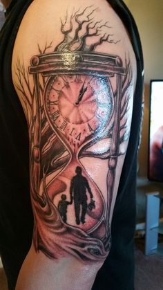 a man with a tattoo on his arm holding a clock and a child walking in the sand