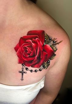 a woman's shoulder with a rose and cross tattoo on the left side of her arm