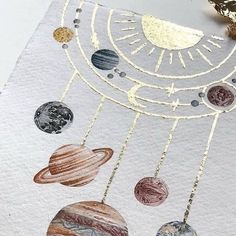 the solar system is made out of paper with gold chains and some planets hanging from it