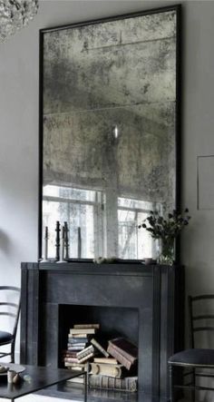 a living room filled with furniture and a large mirror over the fire place in front of a fireplace