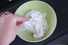 a person is picking up cotton in a green bowl on a black tableclothed surface