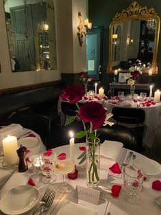 a table set with plates, silverware and candles for valentine's day dinner