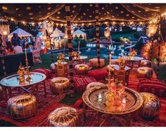 an outdoor event with lots of tables and stools covered in lights, lanterns and decorations