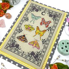 a cross stitch pattern with butterflies on it and some other sewing supplies next to it