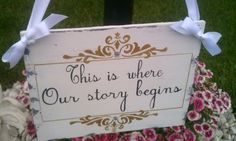 this is where our story begins sign in front of some flowers with ribbons on it