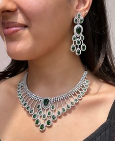 Add a touch of glamour and sophistication with this high quality necklace set in beautiful  emerald green stones. The stones in this set bling and look close to the real thing. This set is sure to make heads turn!  It features an adjustable necklace and a pair of earrings. It can be paired perfectly with both ethnic and western outfits.  In case of any queries, please feel free to reach out. Happy shopping! Formal Emerald Necklace With Cubic Zirconia, Formal Emerald Cubic Zirconia Necklace With Elegant Design, Dazzling Cubic Zirconia Emerald Necklace For Formal Occasions, Formal Cubic Zirconia Emerald Necklace With Elegant Design, Anniversary Emerald Necklace With Cubic Zirconia Jewels, Green Jewelry Sets With Diamond Accents For Party, Hand-set Cubic Zirconia Emerald Necklace For Party, Hand Set Emerald Necklace With Cubic Zirconia For Party, Hand Set Cubic Zirconia Emerald Necklace For Party