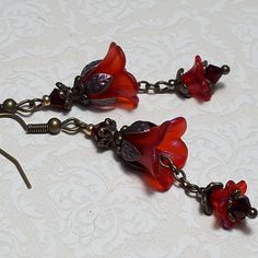 RED BRONZE FLOWER EARRINGS  ▪️▪️▪️▪️▪️▪️▪️️▪️▪️▪️▪️▪️▪️ These pretty red floral earrings are made with cute Lucite flowers that have been painted with an iridescent finish they have matching crystals in pretty Siam red shade and are finished with antique bronze fish hook ear wires and hand painted ornate floral bead caps. They are very light weight and are perfect for special occasions, festivals and bridesmaids yet cute enough for everyday wear.  💜MATERIALS *Lucite Flowers  *Bronze Findings *S Handmade Vintage Flower Earrings, Affordable Red Bohemian Flower Earrings, Cheap Whimsical Red Earrings, Earrings Red, Vintage Handmade Red Flower Earrings, Handmade Vintage Red Flower Earrings, Vintage Red Flower Earrings For Gift, Red Flower Earrings, Pink Gift Box