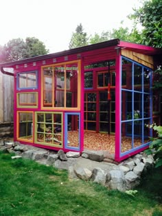 a small colorful building sitting on top of a lush green field