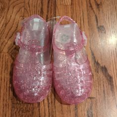 a pair of pink baby shoes sitting on top of a wooden floor next to a bag