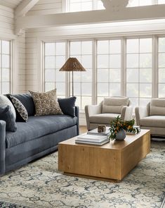 a living room with couches, chairs and a coffee table in front of large windows