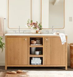 a bathroom vanity with two mirrors above it and some towels on the shelf next to it