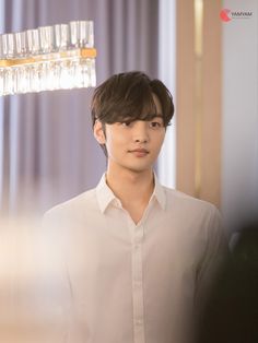 a young man standing in front of a chandelier